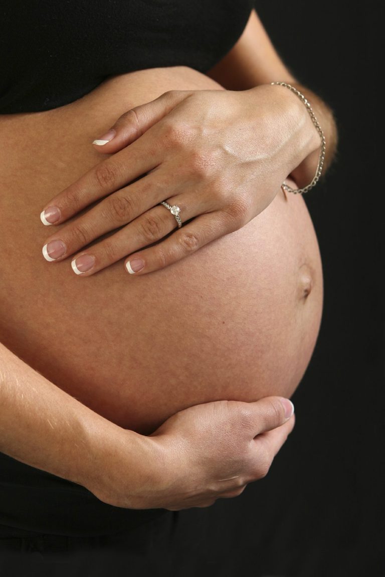 Un ventre de femme enceinte, des mains qui le caressent