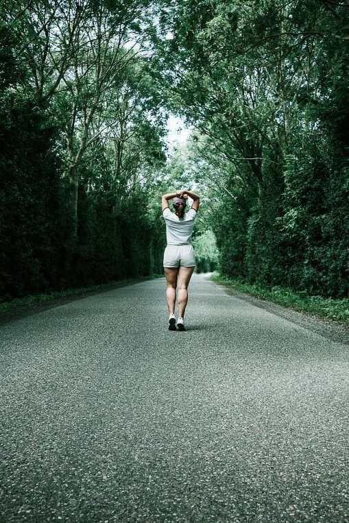 Accepter sa différence, une femme marche de dos sur une route ombragée