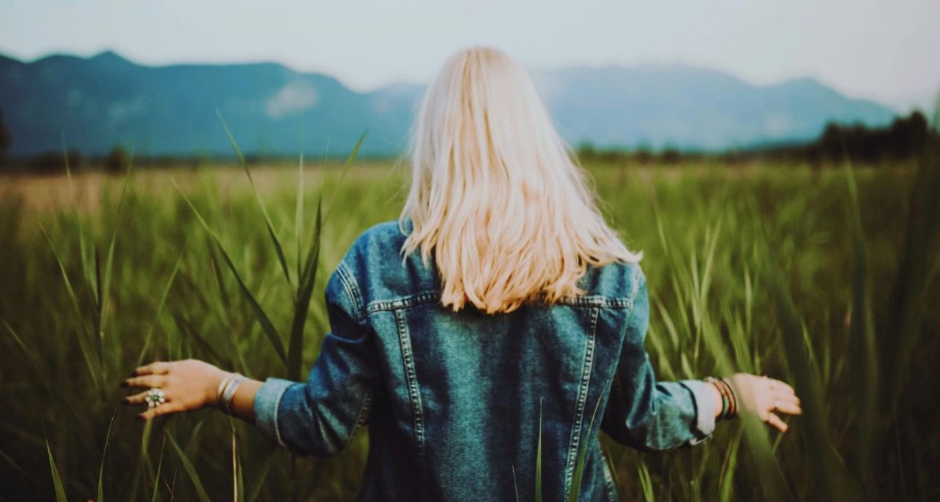 Une femme de dos avance dans un champ, sereine