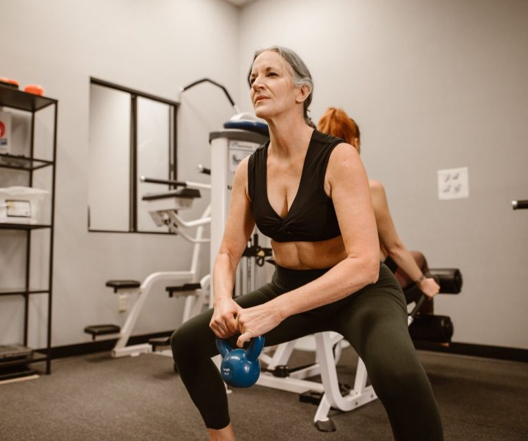 Femme de 50 ans qui fait des squats en soulevant une haltère