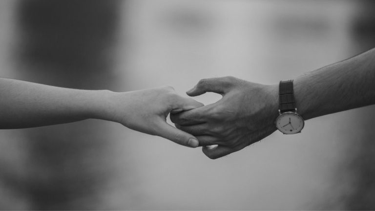 Une main de femme et d'homme qui se tiennent, en noir et blanc 