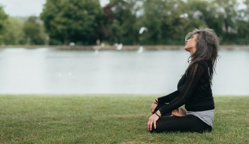 Une femme au bord d'un lac médite, ménopause. 