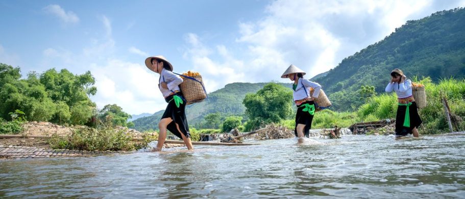 Des femmes asiatiques qui marchent dans l'eau en portant des paniers sur le dos