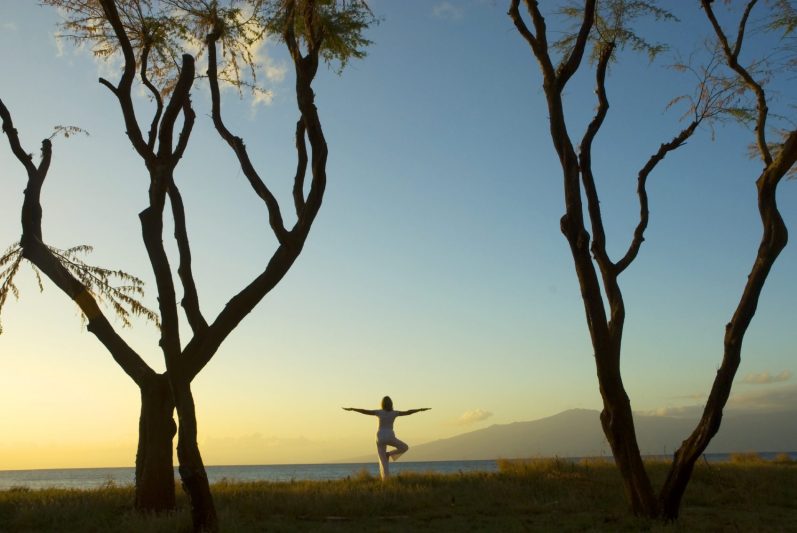 Femme en position de yoga sous un arbre, douleurs articulaires à la ménopause 